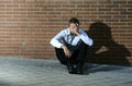 Businessman who lost job lost in depression sitting on city street corner Royalty Free Stock Photo