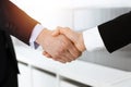 Businessman and woman shaking hands in sunny office, close-up. Concept of handshake as success symbol in business Royalty Free Stock Photo