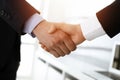 Businessman and woman shaking hands in sunny office, close-up. Concept of handshake as success symbol in business Royalty Free Stock Photo