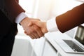 Businessman and woman shaking hands in sunny office, close-up. Concept of handshake as success symbol in business Royalty Free Stock Photo