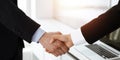 Businessman and woman shaking hands in sunny office, close-up. Concept of handshake as success symbol in business Royalty Free Stock Photo