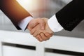 Businessman and woman shaking hands in sunny office, close-up. Concept of handshake as success symbol in business Royalty Free Stock Photo