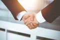 Businessman and woman shaking hands in sunny office, close-up. Concept of handshake as success symbol in business Royalty Free Stock Photo