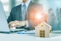 Businessman work on laptop with wooden home model, graph