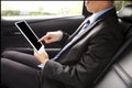Businessman working in back of car and using a tablet Royalty Free Stock Photo
