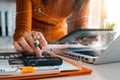 Businessman working on calculator to calculate financial data report, accountancy document and laptop computer at office.