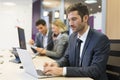 Businessman working on computer in modern office, colleagues in