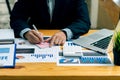 Businessman working on graph papers and laptops using income and expense calculators, accounts or financial auditors to make repor