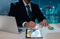 Businessman working at his desk with a laptop, digital tablet, and paperwork. That includes business reports, graphs, charts, as