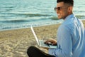 Happy businessman working with laptop on beach. Business trip Royalty Free Stock Photo