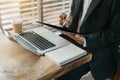 Businessman working laptop computer and holding tablet with coffee cup on table in coffee shop or cafe, working from cafe, Royalty Free Stock Photo