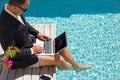 Businessman working with laptop computer by the pool