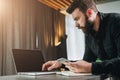 Businessman working on laptop while holding smartphone. Entrepreneur analyzes information, develops business strategy.