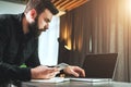 Businessman working on laptop while holding smartphone. Entrepreneur analyzes information, develops business strategy.