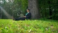 Businessman working on laptop, sitting on grass in park, escaping office routine Royalty Free Stock Photo