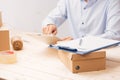 Businessman working with mobile phone and packing brown parcels box at home office