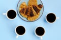 Businessman working morning with cups of hot black coffee and sweet croissant on blue background. Top view, copy space, mockup Royalty Free Stock Photo