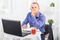 Businessman working in office, sitting at table with a laptop, looking camera Royalty Free Stock Photo