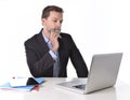 Businessman working in stress at office desk computer laptop reflexive and doubtful pensive and thoughtful Royalty Free Stock Photo