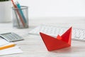 Businessman workspace at desk with red paper ship