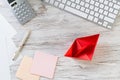 Businessman workspace at desk with red paper ship