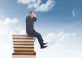 Businessman worried sitting on Books stacked by blue sky Royalty Free Stock Photo