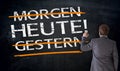 Businessman writes in german Today, Yesterday, Tomorrow on black Royalty Free Stock Photo