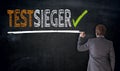 Businessman writes Testsieger in german test winner on blackbo