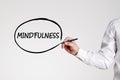 Businessman writes the word mindfulness with an outline circle on gray background. Relaxation and stress free work environment