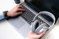 Businessman writing on a gray laptop while holding a gray headphone on a white background