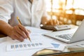 Businessman is writing note on graph paper, analyzing financial report and using calculator Royalty Free Stock Photo