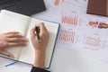 Businessman writing on notebook on wooden table, People are recording accounting data calculated from calculator. To report inform