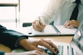 Businessman writing in notepad while his partner using laptop co