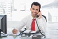 Businessman writing notes while on call at office Royalty Free Stock Photo