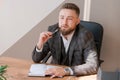 Businessman writing notes while sitting at his desk. Young bearded man Royalty Free Stock Photo