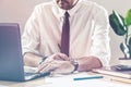 Businessman writing notes and using laptop at office desk Royalty Free Stock Photo