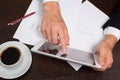 Businessman writing on the paper next to the tablet, coffee, cell phone Royalty Free Stock Photo