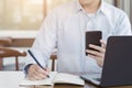 Businessman writing something idea on note or check list and using smartphone with computer laptop, Working and Planning concept Royalty Free Stock Photo