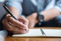 Businessman writing something on notebook in office, hand of man holding pen with signature on paper report. business concepts Royalty Free Stock Photo