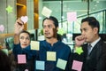 Businessman writing sticking adhesive notes on glass wall in office and team help to creative Royalty Free Stock Photo