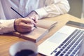 Businessman writing text in notebook and look at opened laptop in cafe, public co-working space. Having business coffee-break Royalty Free Stock Photo