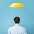 Businessman with a yellow umbrella over him