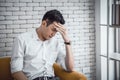 Businessman young asian having a migraine or headache, struggle with dizziness on sitting couch at home