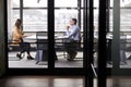 A businessman and young woman meeting for a job interview, full length, seen through glass wall