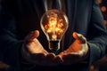 In a businessmans hand, a radiant light bulb sparks innovation Royalty Free Stock Photo