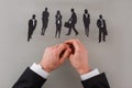 Businessmans hands and paper silhouettes of business people.