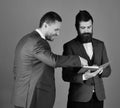 Businessmen with beards discuss business looking into notes. Machos in classic suits talk about schedule. Men with