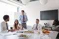 Businessmen And Businesswomen Meeting In Modern Boardroom Over Working Lunch