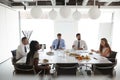 Businessmen And Businesswomen Meeting In Modern Boardroom Over Working Lunch