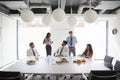 Businessmen And Businesswomen Meeting In Modern Boardroom Over Working Lunch